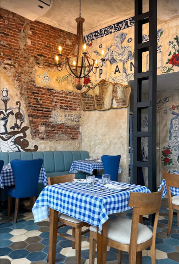 Salón de Cantina di Pani con manteles a cuadros azules y paredes ilustradas