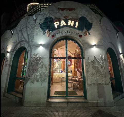 Fachada de PANI Pizza Feroz de noche, con su puerta en arco
